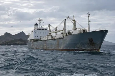 AI-generated illustration: An unmarked refrigerated cargo ship near dark volcanic islands.